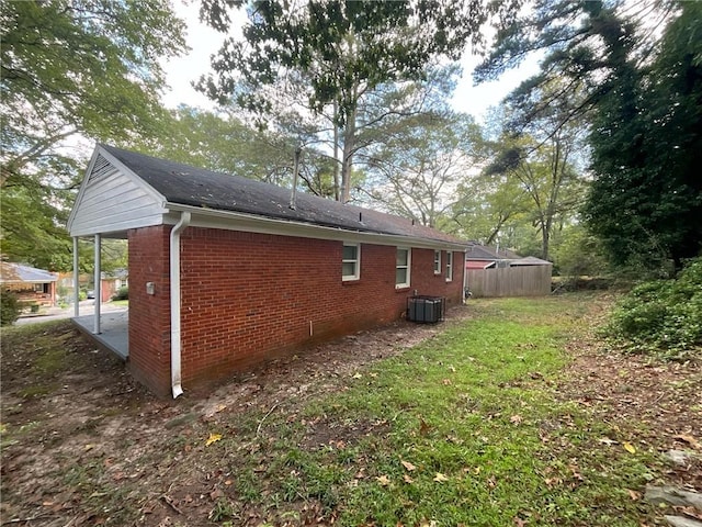 view of side of home with a lawn and central air condition unit