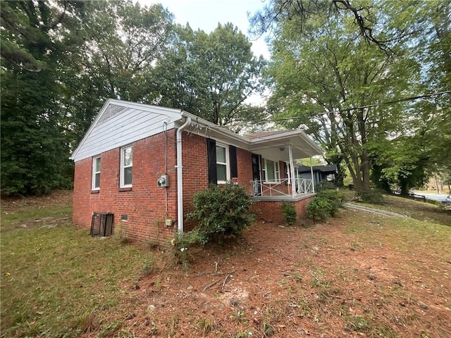 view of side of property featuring a lawn and covered porch