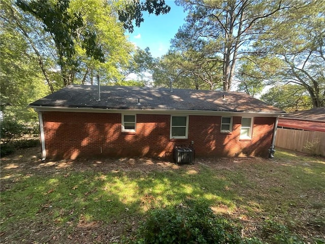 rear view of property featuring a lawn and central AC