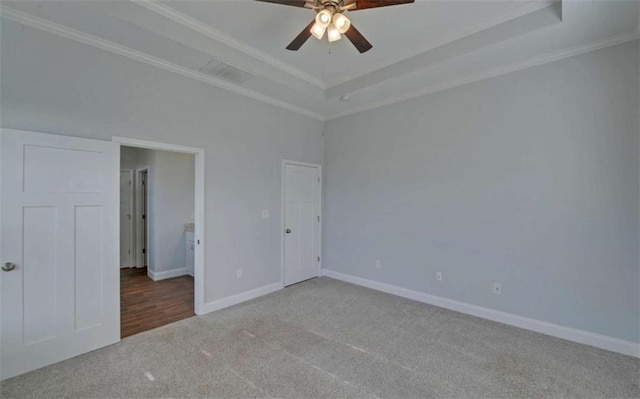 unfurnished bedroom featuring crown molding, carpet floors, a raised ceiling, and ceiling fan