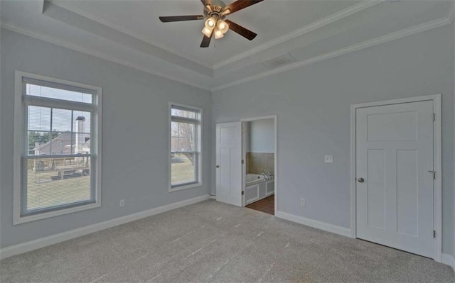 unfurnished bedroom featuring crown molding, ensuite bath, a tray ceiling, and light carpet