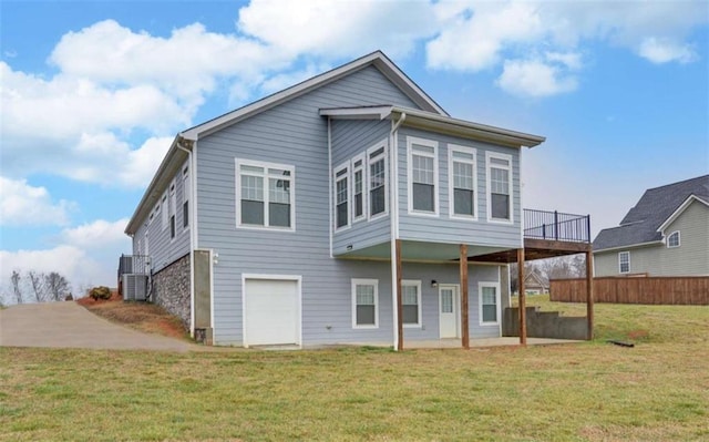 back of house with a garage, a wooden deck, a yard, and cooling unit