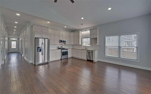 kitchen with appliances with stainless steel finishes, dark hardwood / wood-style floors, lofted ceiling, sink, and white cabinets