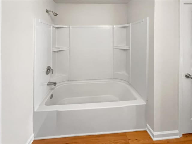 bathroom with wood-type flooring and washtub / shower combination