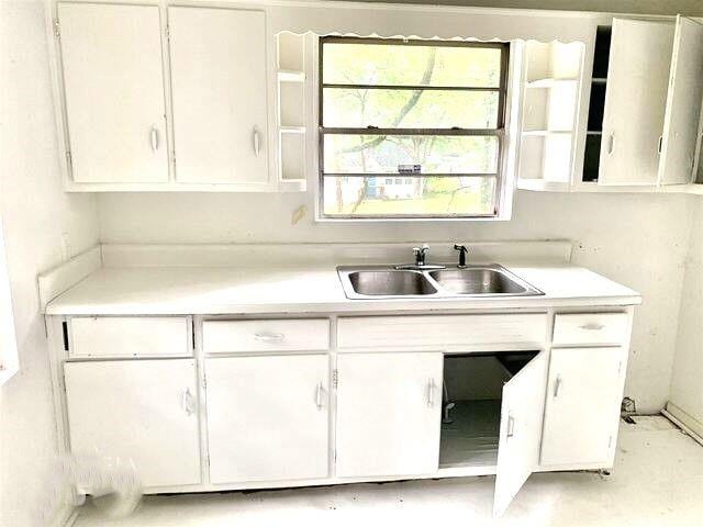 kitchen with a sink, white cabinets, and light countertops