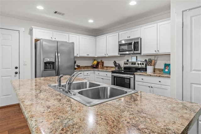 1081 Oak Hill Ln, Madison, GA 30650 - kitchen with appliances with stainless steel finishes, a sink, white cabinets, a kitchen island with sink, and ornamental molding