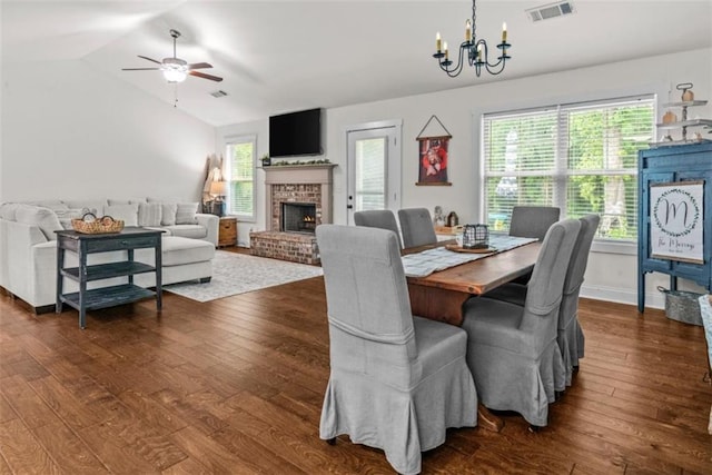 1081 Oak Hill Ln, Madison, GA 30650 - dining space with dark wood-style floors, a ceiling fan, a chandelier, a brick fireplace, and vaulted ceiling