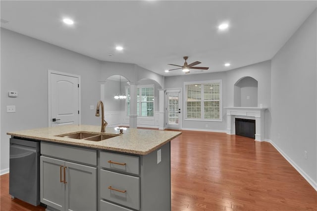 kitchen featuring an island with sink, open floor plan, a sink, gray cabinetry, and stainless steel dishwasher