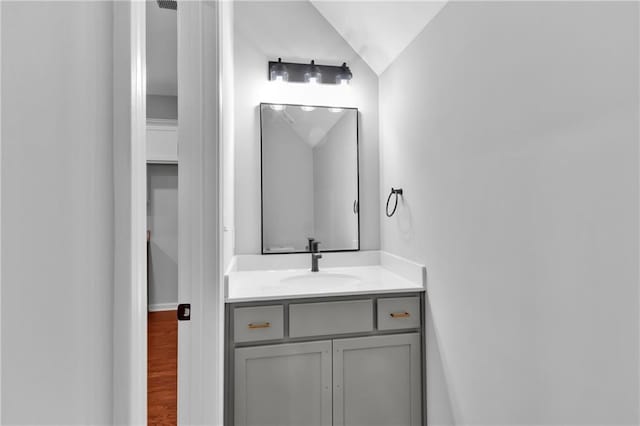 bathroom with lofted ceiling, wood finished floors, and vanity