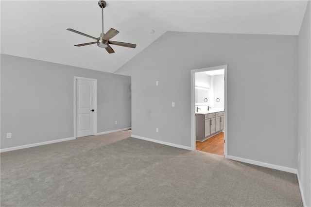 unfurnished bedroom with lofted ceiling, light carpet, baseboards, and ensuite bathroom