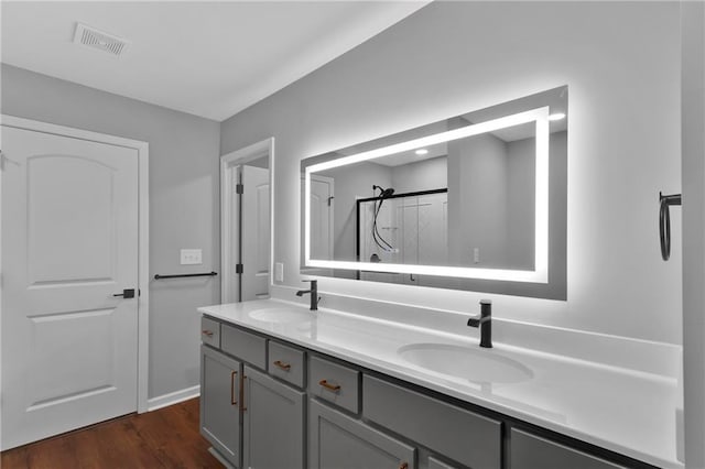 full bath with visible vents, a sink, a shower stall, and double vanity