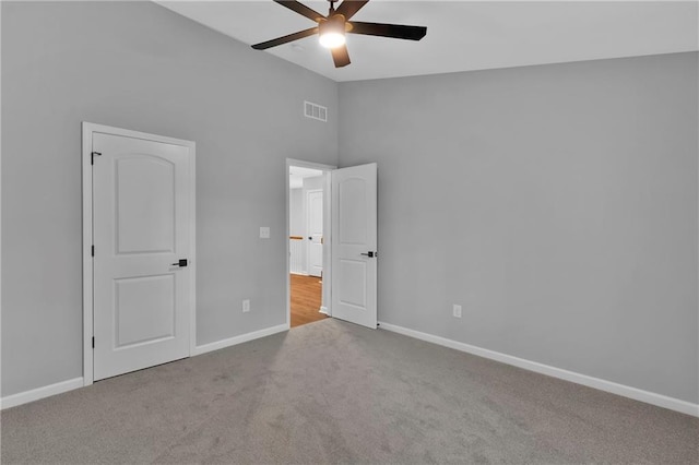 unfurnished bedroom featuring lofted ceiling, light colored carpet, visible vents, a ceiling fan, and baseboards