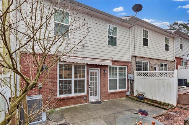 rear view of house featuring a patio, brick siding, cooling unit, and fence