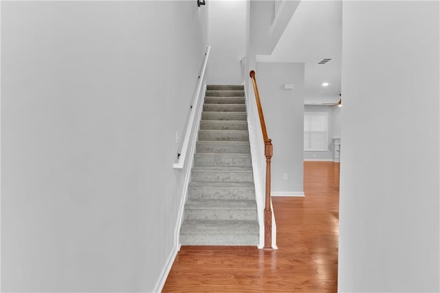 stairs with a ceiling fan, baseboards, and wood finished floors