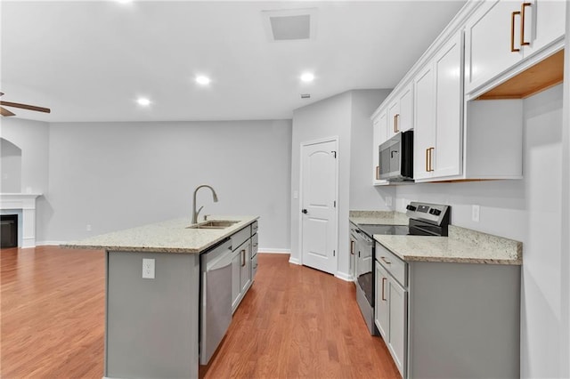 kitchen featuring a center island with sink, visible vents, light stone counters, stainless steel appliances, and a sink