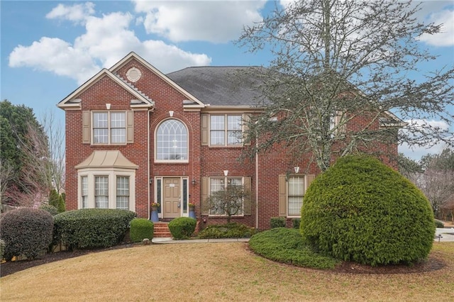 view of front facade featuring brick siding and a front yard