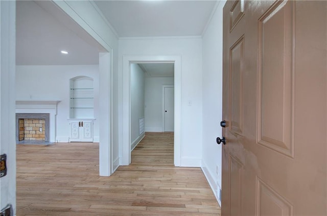 hall with light hardwood / wood-style flooring, built in features, and ornamental molding