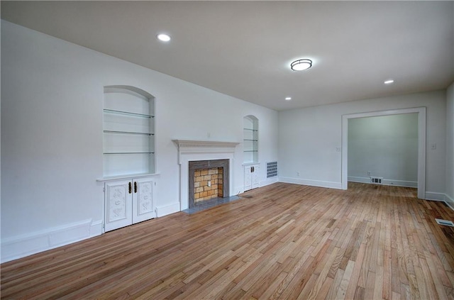 unfurnished living room featuring light wood-type flooring and built in features