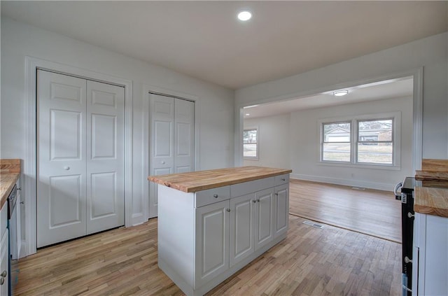 kitchen with wood counters, a kitchen island, white cabinetry, and light hardwood / wood-style flooring