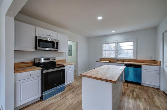 kitchen with wooden counters, stainless steel appliances, white cabinetry, and a kitchen island