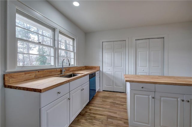 kitchen featuring white cabinetry, sink, stainless steel dishwasher, and wood counters