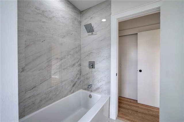 bathroom with wood-type flooring and tiled shower / bath