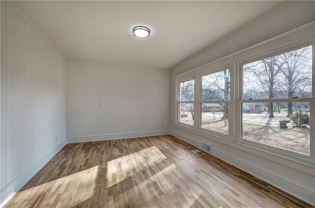 empty room with wooden walls and light hardwood / wood-style floors