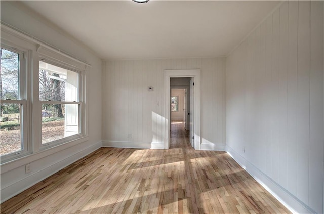 empty room with light hardwood / wood-style floors and wood walls