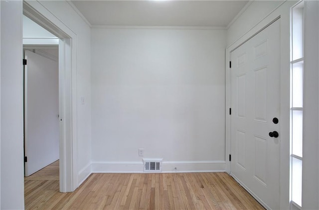 empty room featuring light wood-type flooring and crown molding