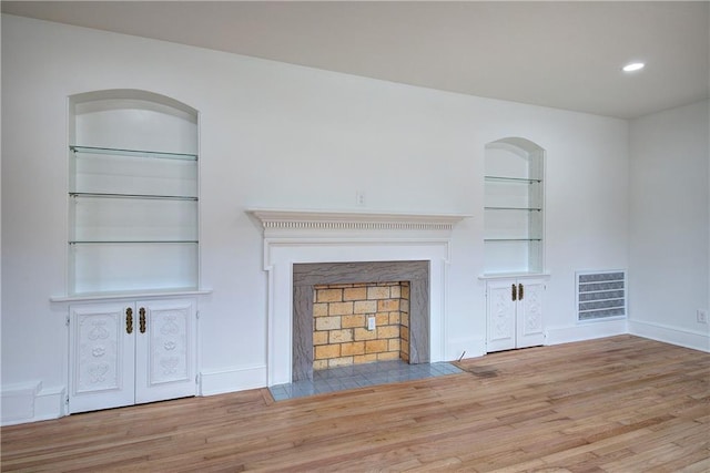 unfurnished living room with built in features and light wood-type flooring