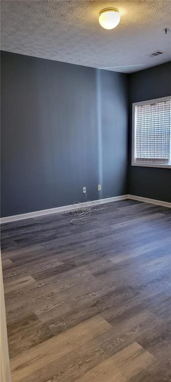 unfurnished room featuring dark hardwood / wood-style floors and a textured ceiling