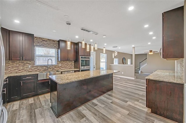 kitchen featuring dark brown cabinetry, a kitchen island, decorative backsplash, and a sink