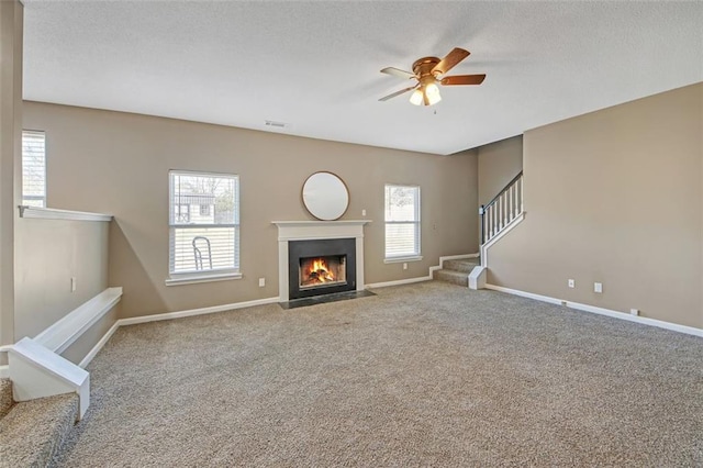 unfurnished living room with carpet flooring, stairway, baseboards, and a textured ceiling