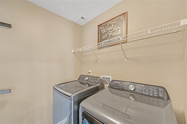 clothes washing area featuring laundry area, visible vents, separate washer and dryer, and a textured ceiling