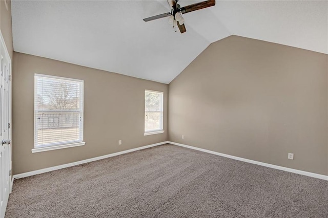 carpeted spare room featuring lofted ceiling, ceiling fan, and baseboards