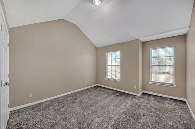 empty room with lofted ceiling, carpet flooring, and baseboards