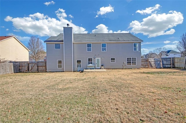 rear view of property featuring a fenced backyard, a yard, and a chimney