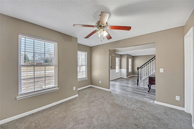 empty room with carpet floors, stairs, baseboards, and a textured ceiling