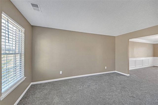 carpeted spare room with baseboards, plenty of natural light, visible vents, and a textured ceiling