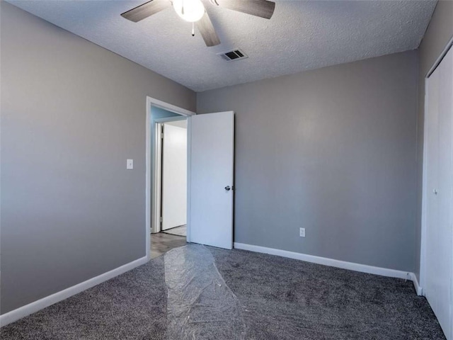 carpeted spare room featuring baseboards, a textured ceiling, visible vents, and a ceiling fan