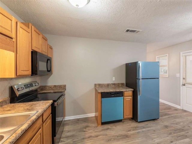 kitchen featuring stainless steel appliances, light wood-type flooring, visible vents, and baseboards