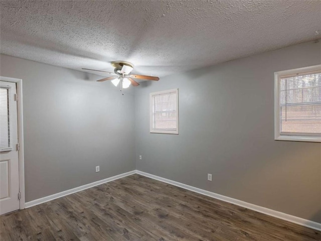 unfurnished room with dark wood-style flooring, a healthy amount of sunlight, and baseboards