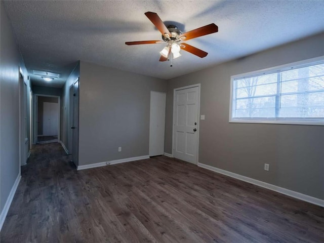 spare room featuring ceiling fan, a textured ceiling, baseboards, and dark wood-style flooring