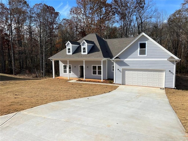 view of front of home featuring a front lawn, covered porch, driveway, and roof with shingles