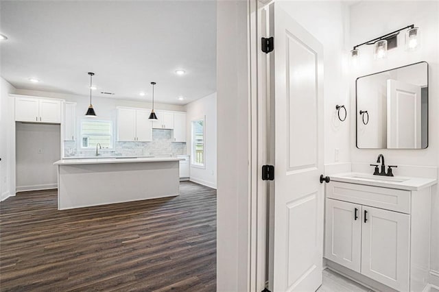 kitchen with white cabinetry, sink, a kitchen island, and pendant lighting