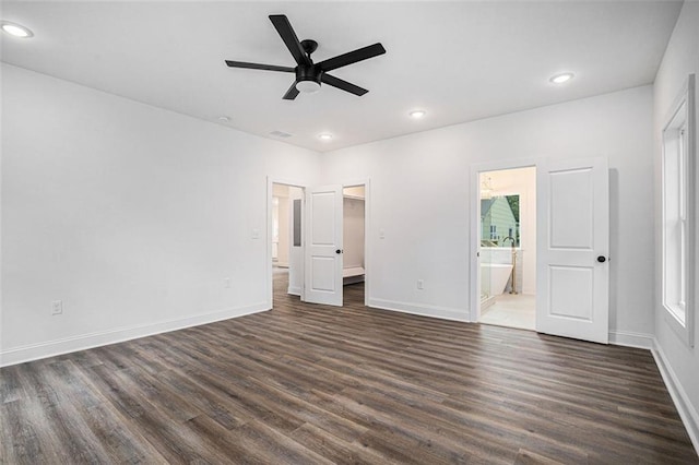 unfurnished bedroom with multiple windows, dark hardwood / wood-style flooring, connected bathroom, and ceiling fan