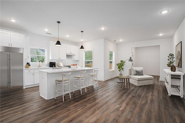 kitchen featuring white cabinets, a kitchen island, decorative light fixtures, and stainless steel built in refrigerator