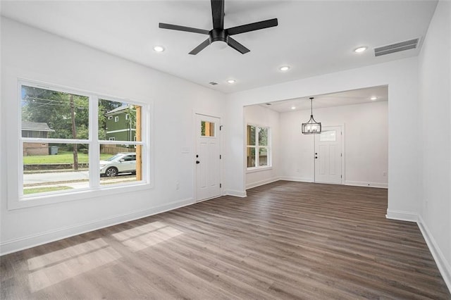 interior space featuring ceiling fan with notable chandelier and dark wood-type flooring