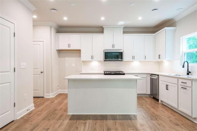 kitchen featuring stainless steel appliances, a sink, tasteful backsplash, white cabinets, and a kitchen island
