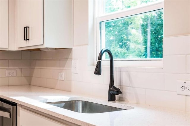 kitchen with white cabinetry, light stone countertops, sink, and decorative backsplash